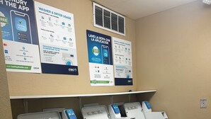 A laundromat with four washing machines and instructional posters on the wall.