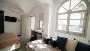 A bedroom with a bed, a desk, and a large arched window. - Blue Arise Fira (Santorini)