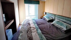Une chambre à coucher comprenant un lit, des tables de chevet, un bureau et une armoire.