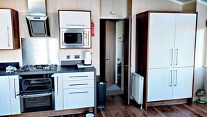 Une cuisine compacte équipée d’un four à micro-ondes, d’une cuisinière, d’un four et de placards.