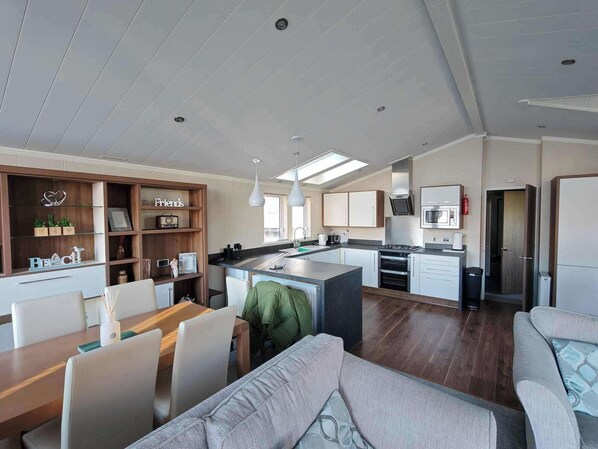 Een moderne keuken met een centraal eiland, witte kasten en een eethoek met een houten tafel en stoelen.