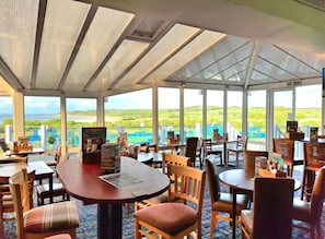 Un ristorante con tavoli e sedie, ampie finestre e vista sul paesaggio.