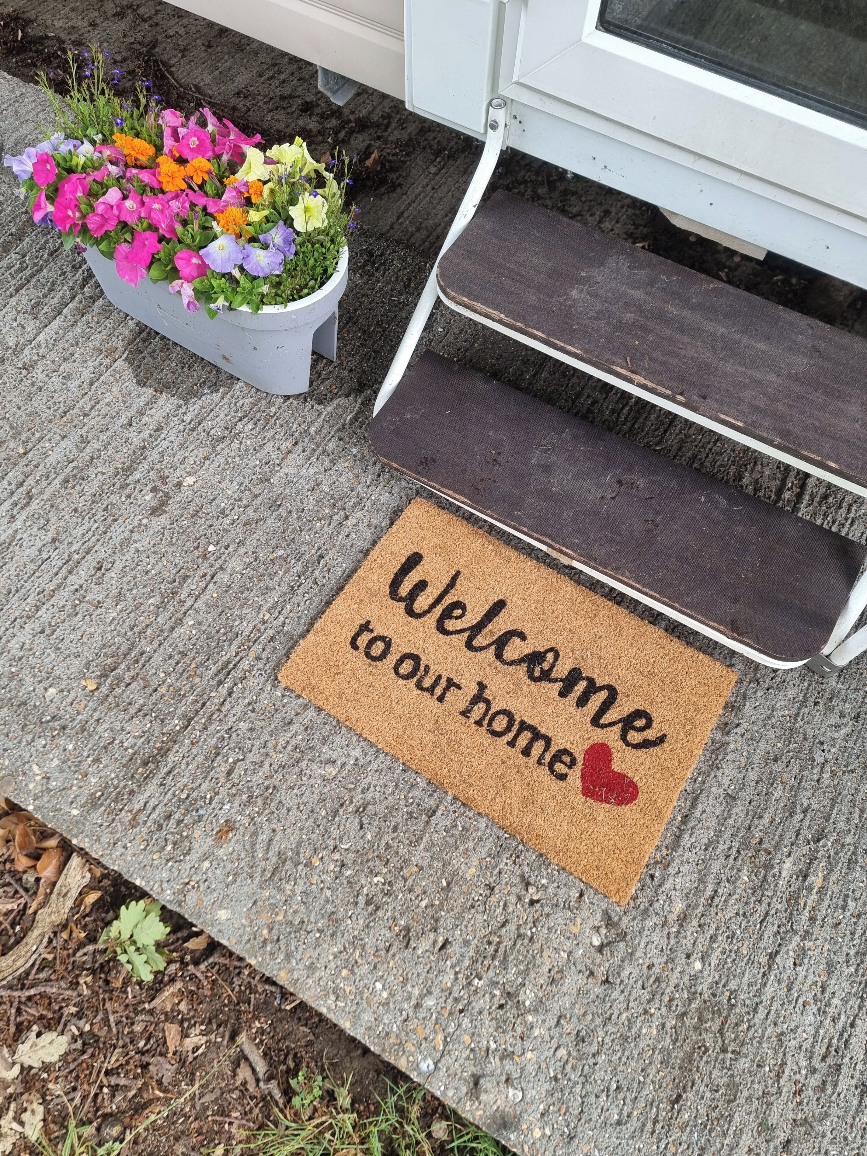 A welcome mat with "Welcome to our home" text and a red heart symbol.