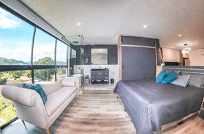 Relax in this serene bedroom with a large bed, sofa, and stunning view of the surrounding landscape.