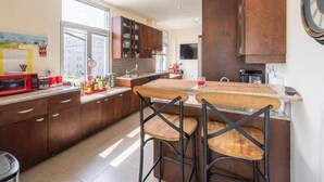 A modern kitchen with dark wooden cabinets, a large window, and a bar area with stools. - Sleeps6-apartment-parking-balcony-patio (Madrid)
