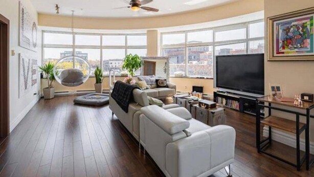 A modern living room with a large window, a ceiling fan, a sofa, a TV, and a bookshelf. - Sleeps6-apartment-parking-balcony-patio (Madrid)