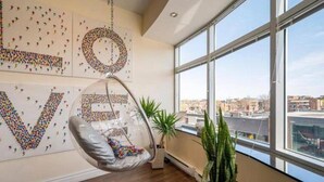 A modern room with a large window, a hanging chair, and a wall art piece spelling out "LOVE". - Sleeps6-apartment-parking-balcony-patio (Madrid)