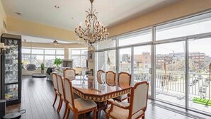 A dining area with a large table and chairs, a chandelier, and large windows offering a city view. - Sleeps6-apartment-parking-balcony-patio (Madrid)