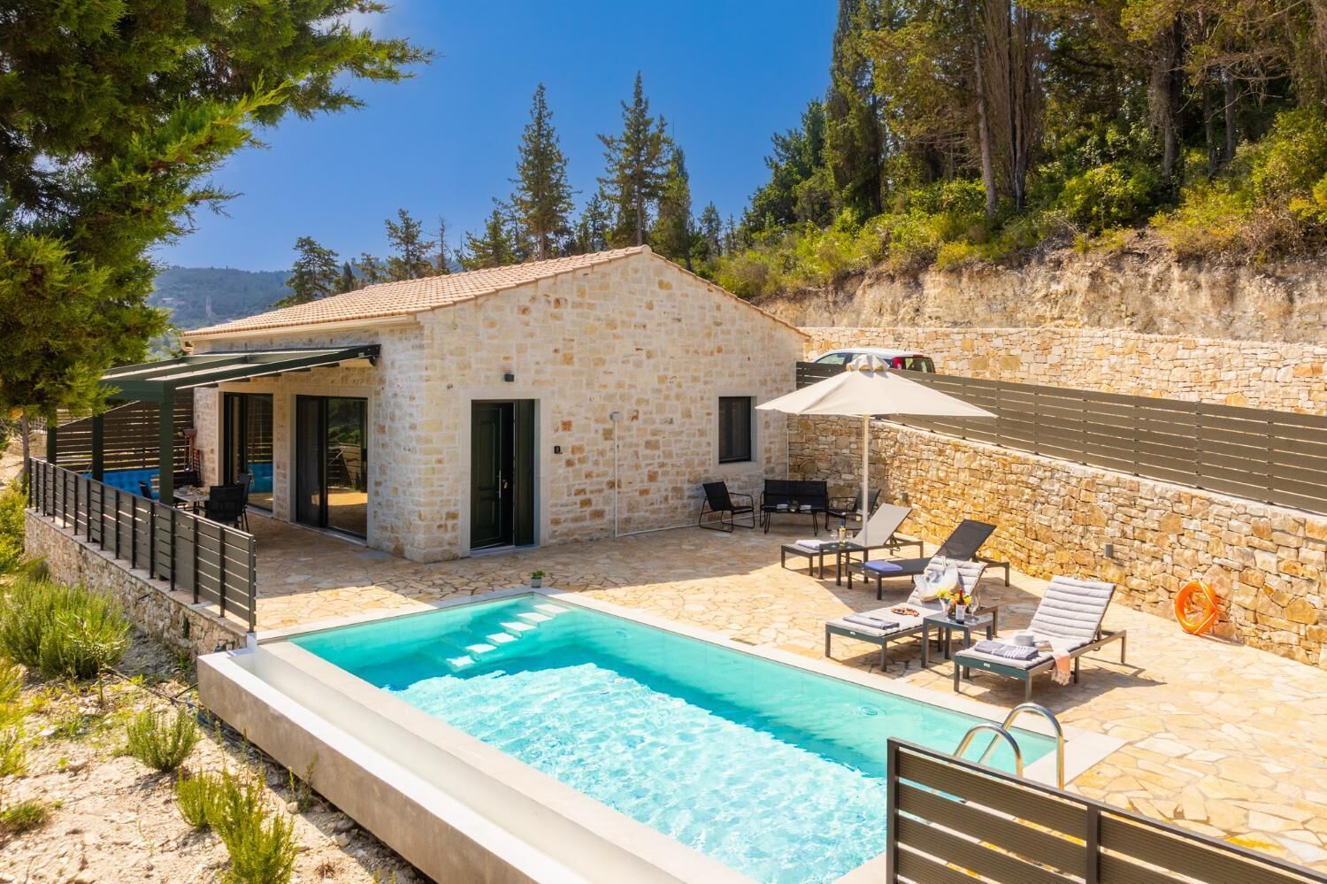 A stone house with a swimming pool, outdoor seating, and a covered patio.