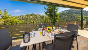 Mesa lista para comer con vista a una cadena montañosa boscosa.