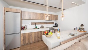 Una cocina moderna con armarios de madera, un refrigerador de acero inoxidable, una cafetera y una cesta de frutas en la encimera.