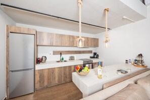 Een moderne keuken met houten kastjes, een roestvrijstalen koelkast, een koffieapparaat en een mand met fruit op het aanrecht.