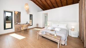 Un dormitorio amplio con una cama grande, un escritorio de madera y una zona de estar.
