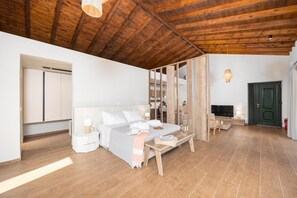 A modern bedroom with a wooden ceiling, a bed, a TV, and a wardrobe.