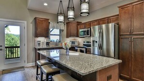 Una cocina moderna con encimeras de granito, electrodomésticos de acero inoxidable y armarios de madera.