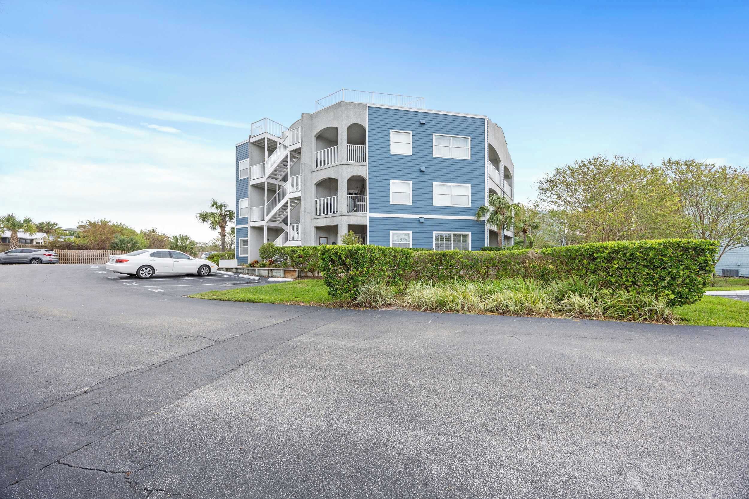 A multi-story residential building with balconies and a parking area.