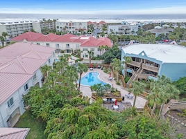 Um resort com piscina rodeada por palmeiras e vista para o oceano.