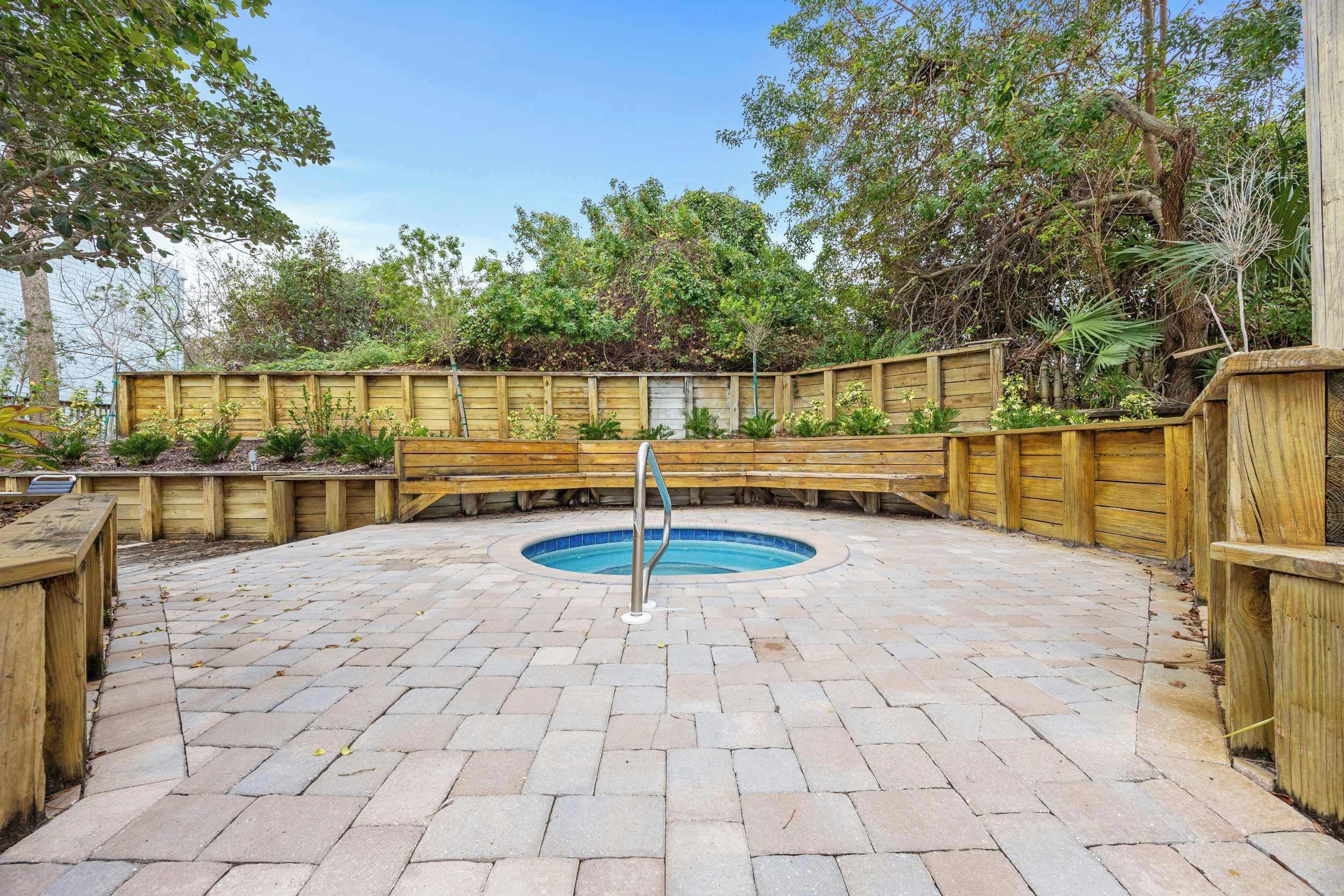 A wooden deck with a pool, surrounded by a wooden fence and lush greenery.