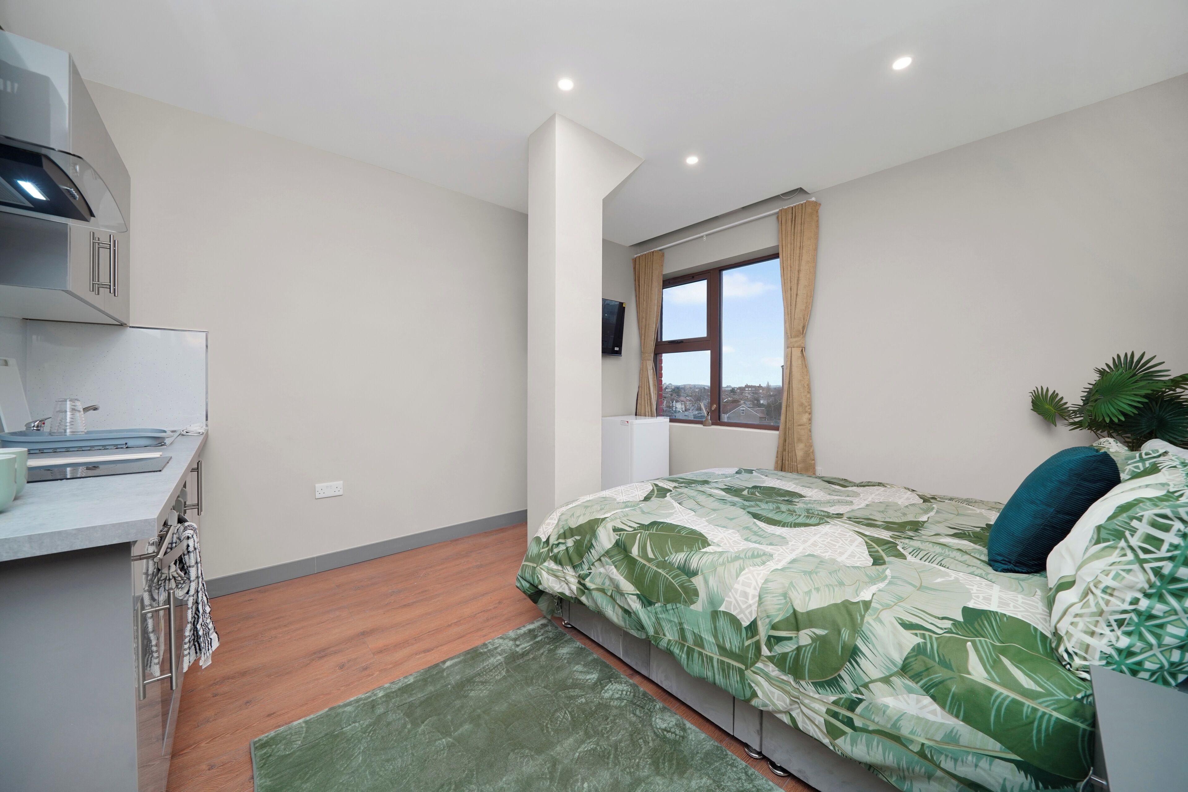 A bedroom with a bed, a desk, and a window with a view.