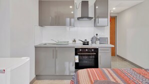 Una cocina compacta con electrodomésticos de acero inoxidable, horno empotrado y una pequeña encimera.