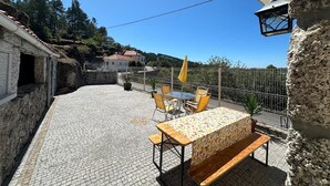 Eine Terrasse mit Tisch, Stühlen, einer Lampe und Blick auf ein Haus im Hintergrund.