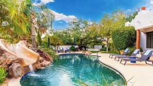 Una piscina con cascata, sedie a sdraio e palme.