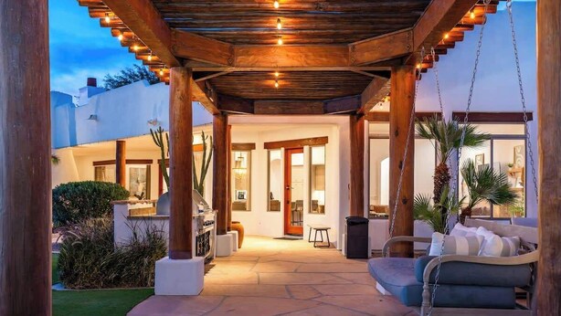 Un'area patio esterna con una pergola in legno, un'amaca e un angolo salotto.