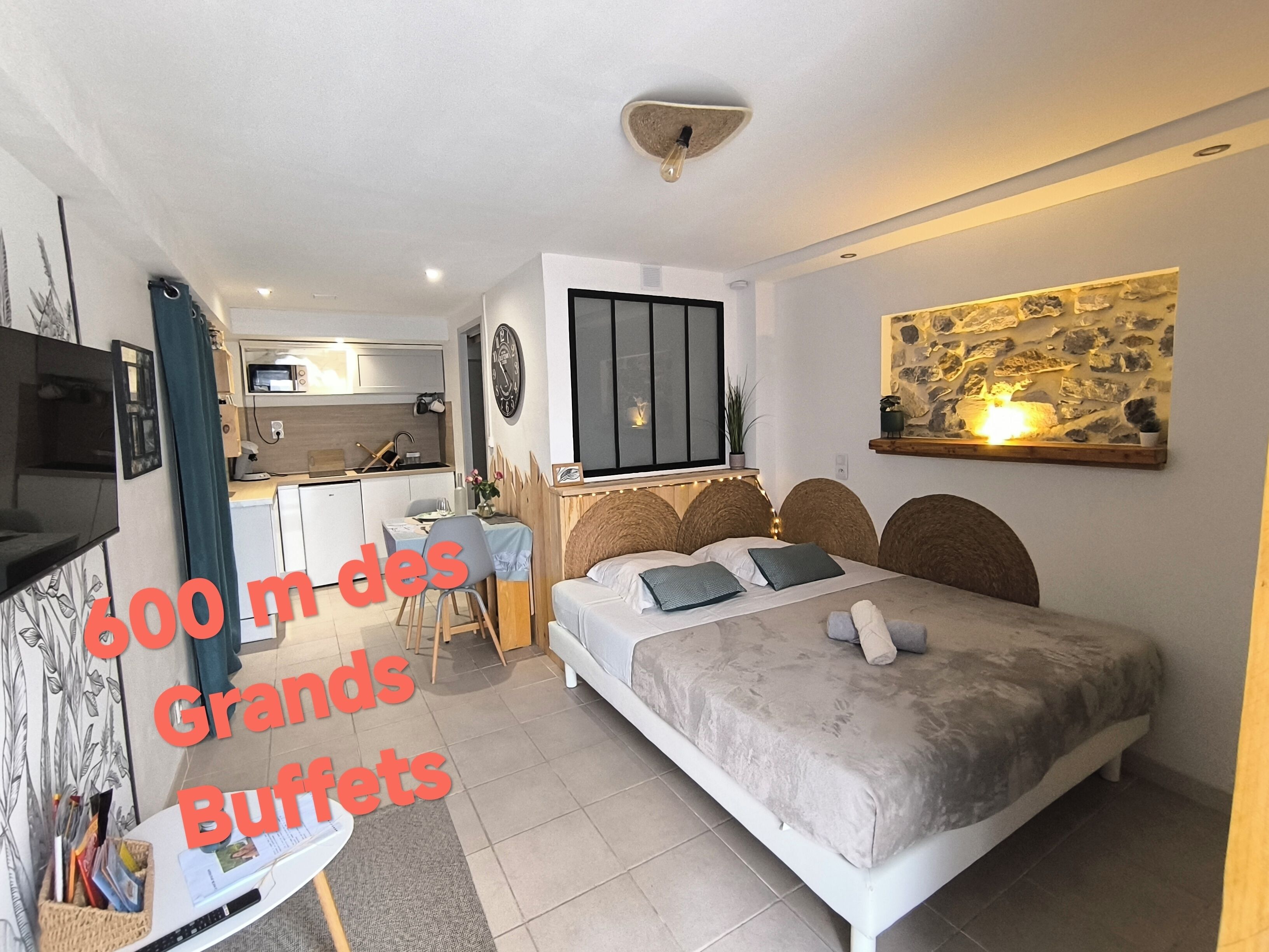 Une chambre compacte comprenant un lit, un bureau et une kitchenette.