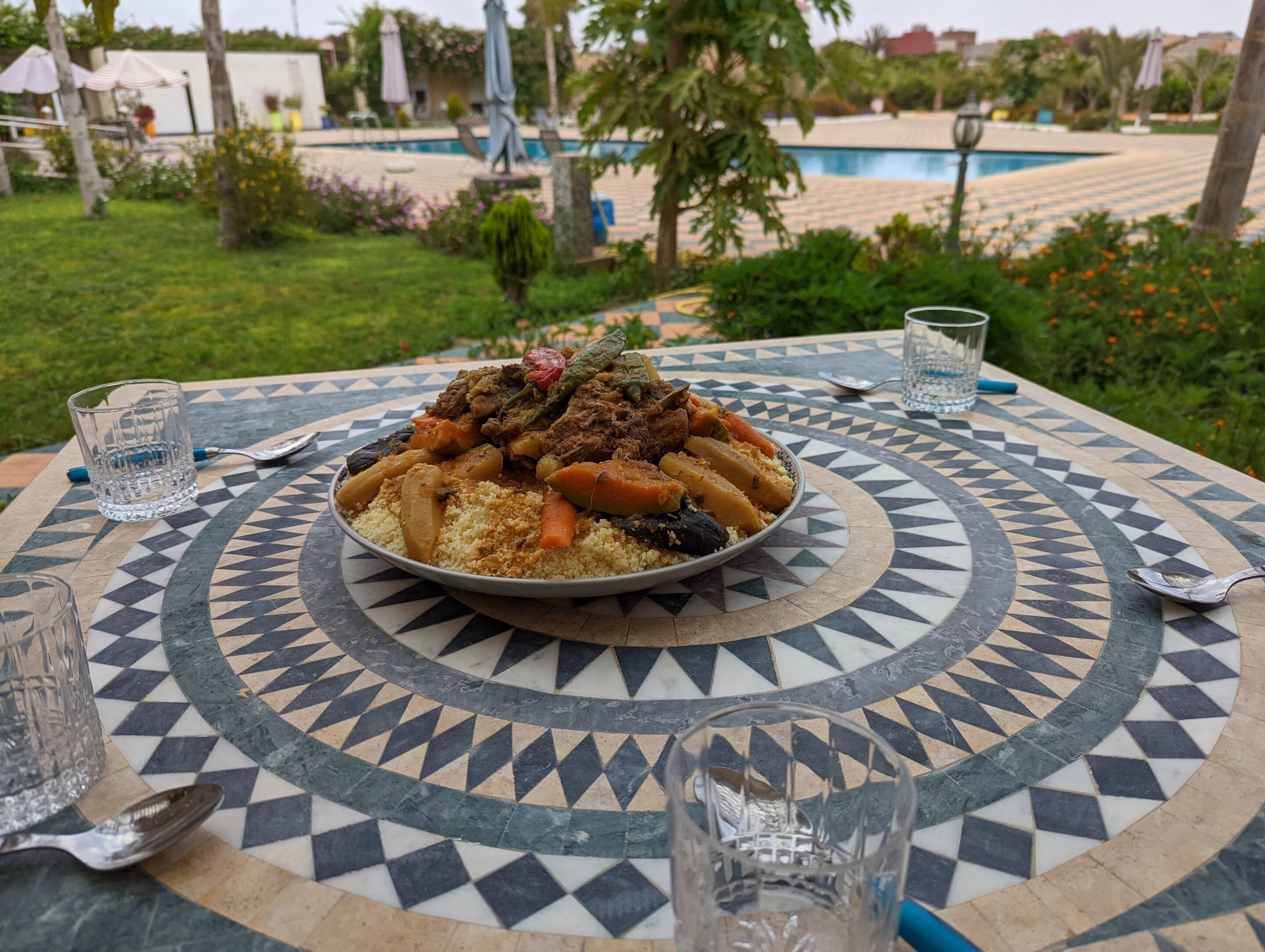 Una mesa de comedor con mantel estampado, un plato de comida y dos vasos de agua.