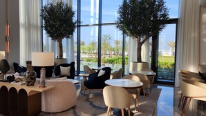 Un espace de détente moderne avec des tables rondes, des sièges confortables et deux grands arbres.