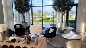 Ein moderner Lounge-Bereich mit runden Tischen, bequemen Sitzgelegenheiten und großen Fenstern mit Blick auf einen angelegten Garten.