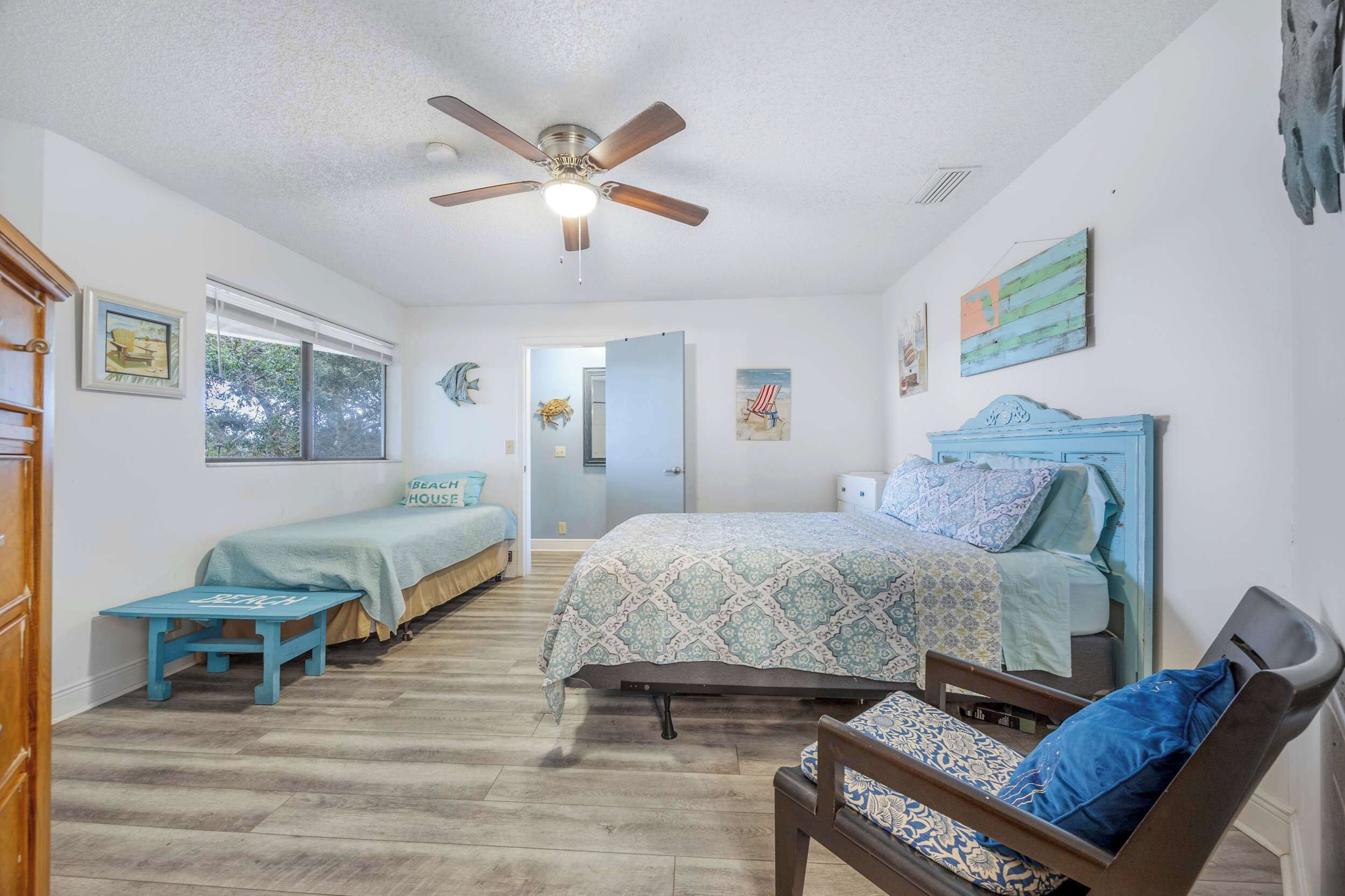 A bedroom with a bed, a chair, a desk, and a ceiling fan.