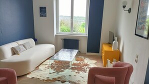 A modern living room with a white sofa, a glass coffee table, a cowhide rug, and a yellow side table.