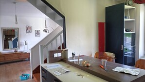 A kitchen with a dining table, chairs, and a staircase leading to another room.
