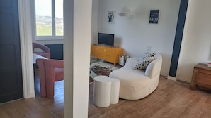A living room with a sofa, a television, a yellow cabinet, and a window.