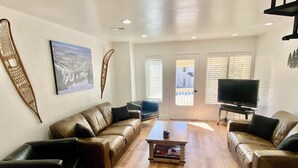 A living room with a brown leather sofa, a coffee table, and a TV on a stand.