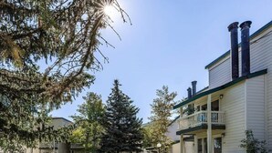 A two-story building with a balcony on the second floor, a covered patio, and a well-maintained lawn.