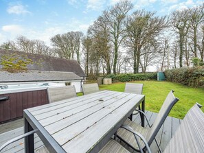 A wooden table and chairs in a garden with a house in the background.