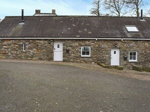 A stone building with a white door, a small window, and a chimney.