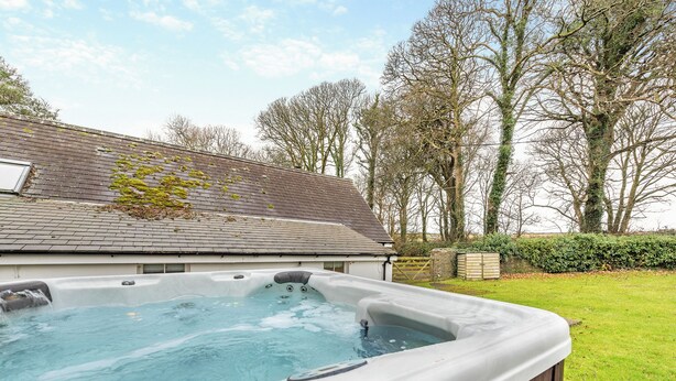 A hot tub in a backyard with a house in the background. - 3 bedroom accommodation in Roch (Roch)
