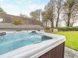 A hot tub in a backyard with a house in the background.
