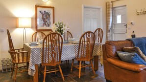 A dining area with a table set for four, wooden chairs, a vase of flowers, and a painting on the wall. - 3 bedroom accommodation in Roch (Roch)