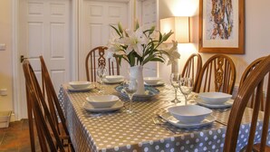 Une salle à manger avec une nappe à pois, un centre de table floral blanc et des chaises en bois.
