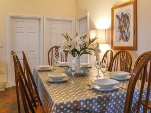 A dining room with a polka dot tablecloth, white floral centerpiece, and wooden chairs. - 3 bedroom accommodation in Roch (Roch)