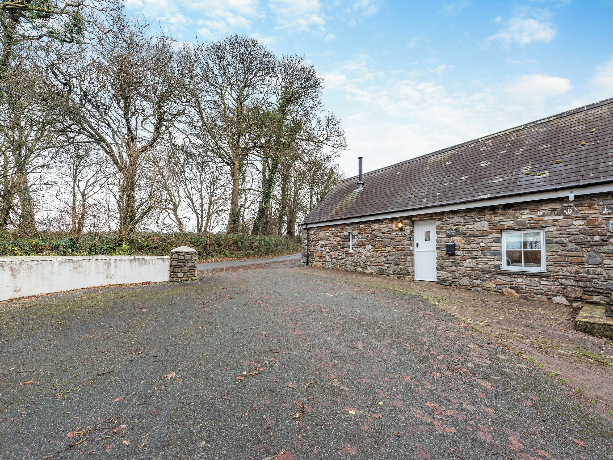 A stone building with a gravel driveway and a white door.