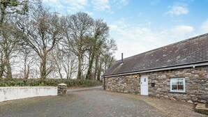 A stone building with a gravel driveway and a white door. - 3 bedroom accommodation in Roch (Roch)