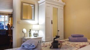 Un lit bien fait, avec des serviettes pliées, une table de chevet avec une lampe, un miroir et un vase décoratif.