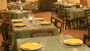A restaurant with multiple tables set for dining, featuring green tablecloths and candles. - Nice Apartment in Guasticce With Pool (Collesalvetti)