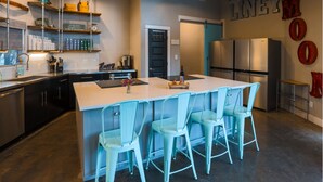 A modern kitchen with a large island, bar stools, stainless steel appliances, and decorative wall letters. - The Liney Moon (Dripping Springs)