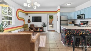 Een moderne keuken met een gebogen kookeiland, een flatscreen-tv en een zithoek met een bank en een gitaar.